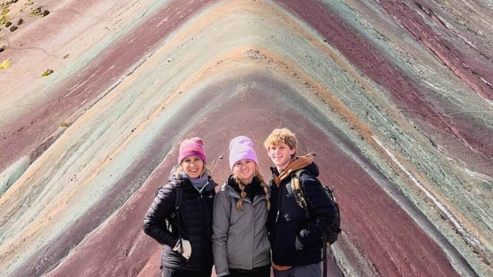 A group of people standing in front of a multicolored geological formation. 5