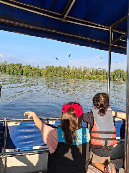 Two people on a boat, one pointing at birds flying over water. 2