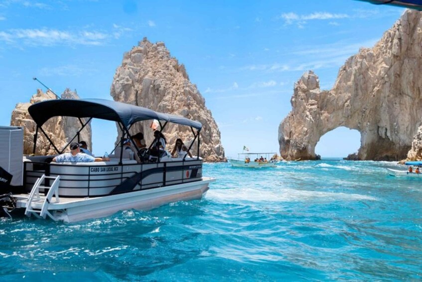 A boat with passengers near a rock formation with an arch. 1