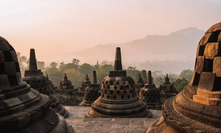 Ancient stone stupas in a misty landscape with mountains in the background. 5