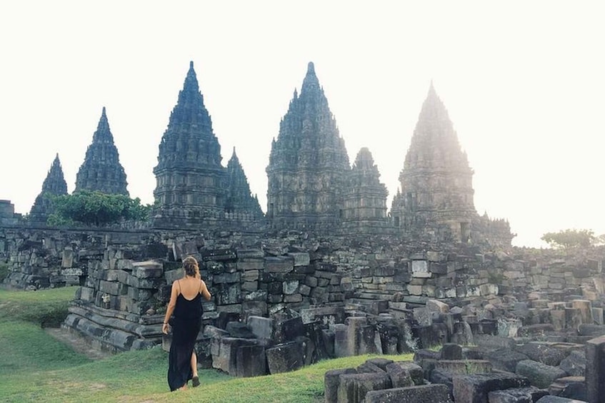 A person walking towards ancient stone structures with multiple pointed towers. 2