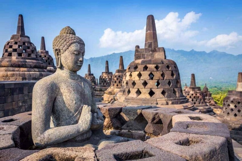 A stone Buddha statue surrounded by ancient stupa structures. 1