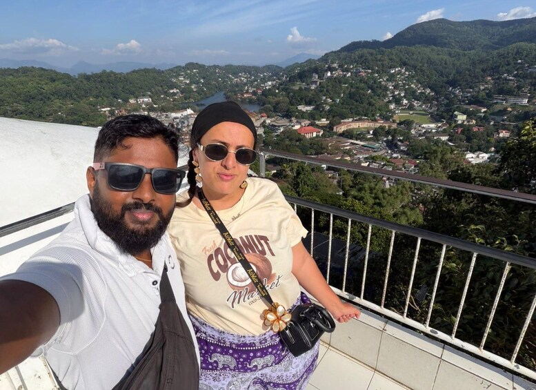 A person taking a selfie with a scenic view of a town and mountains in the background. 2
