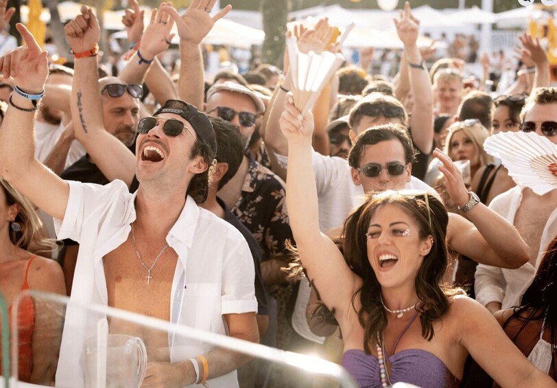 A crowd at an outdoor event with people raising their hands and cheering. 4
