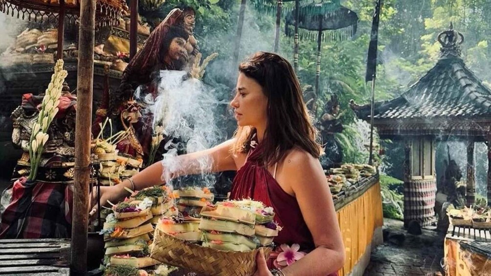 A person performing a ritual with offerings at a traditional altar in a forested area. 1