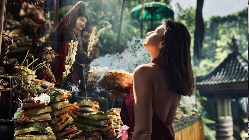 A person in traditional attire at a temple, surrounded by incense and offerings. 3