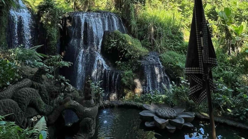 A waterfall surrounded by lush greenery and a pond with lotus flowers. 2