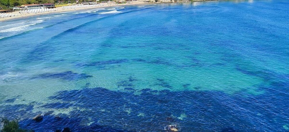 A coastal beach with clear blue waters and a sandy shore. 3