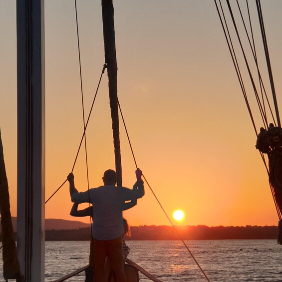 A person on a boat during sunset, with the sun setting on the horizon. 2