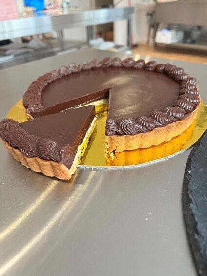 A chocolate tart with a slice missing on a golden plate. 5