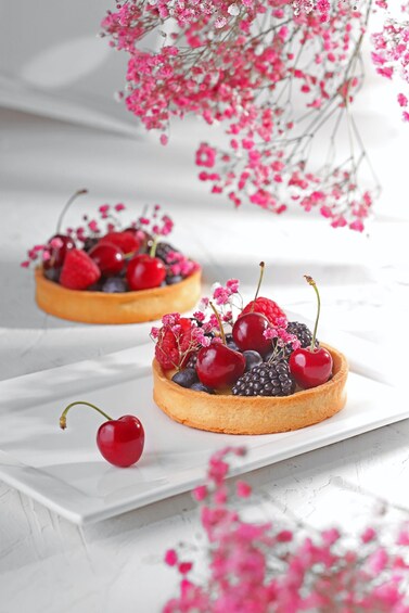 Two tartlets with berries and cherries on a white plate. 1