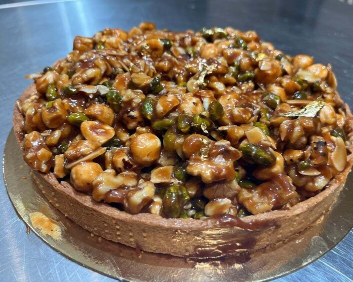 A pizza topped with various vegetables and nuts on a metal surface. 2