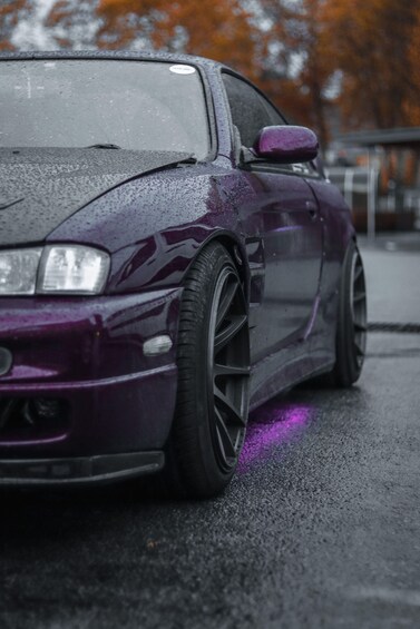 A purple car with purple underglow lights on a wet road. 5
