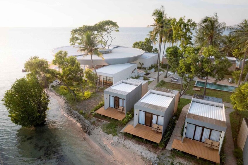 A coastal resort with modern villas, a beach, and palm trees. 1