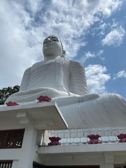 A large white statue of a seated figure with lotus flowers in front. 1