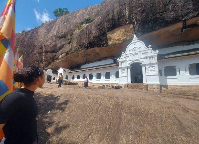 A white colonial-style building with a large rock formation in the background. 3