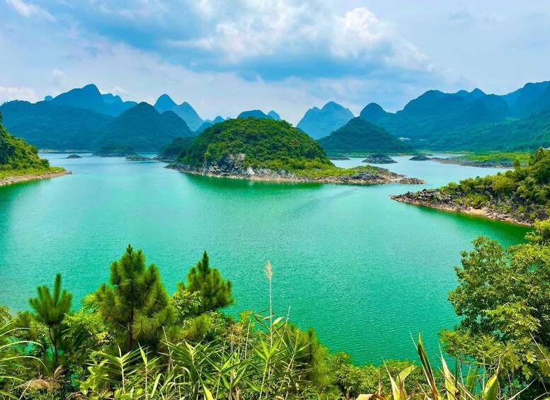 A turquoise lake surrounded by lush green hills and mountains. 1