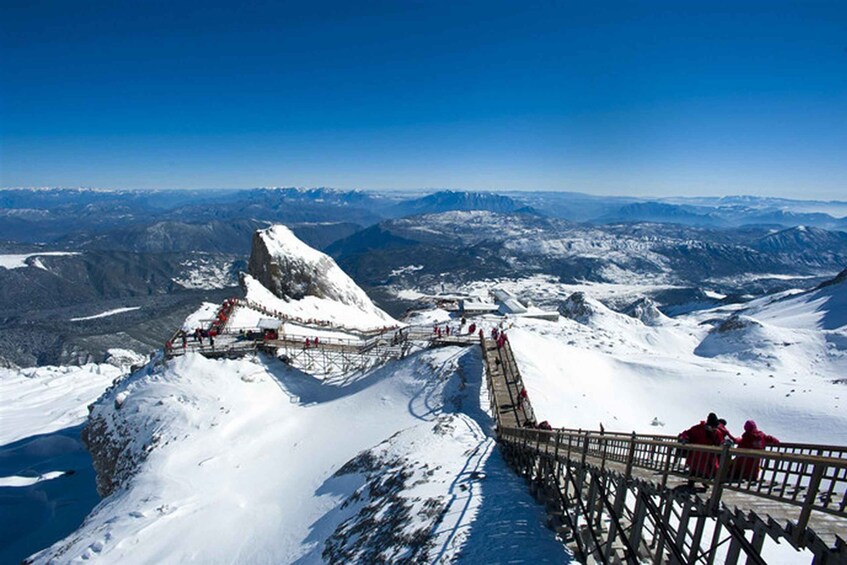 A snow-covered mountain with a wooden viewing platform and a clear blue sky. 3