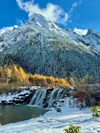 A snow-covered mountain range with a waterfall and a river. 2