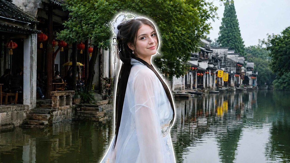 A person in traditional attire standing by a waterway with historic buildings and red lanterns. 1