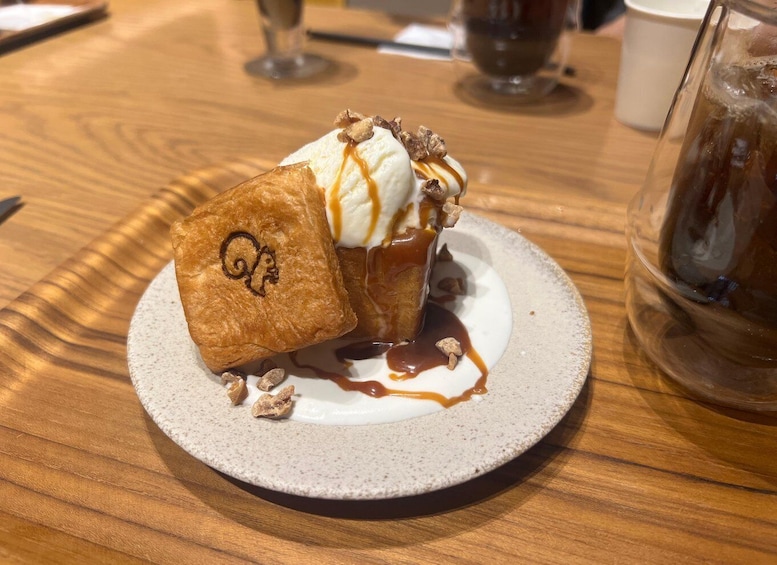 A plate with a piece of toast topped with ice cream and caramel sauce, accompanied by a glass of iced tea. 4