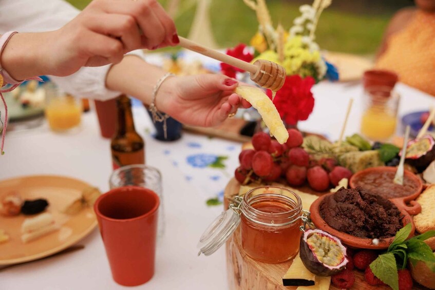 A person dipping a banana into honey using a honey dipper. 4