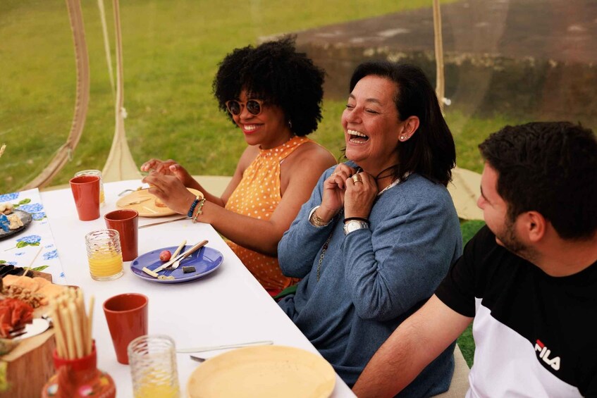 A group of people sitting at an outdoor table with food and drinks. 3