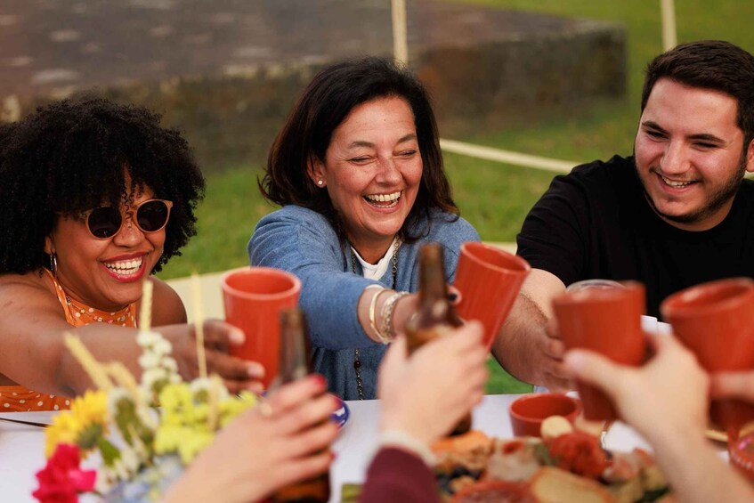 Three people toasting with red cups at an outdoor gathering. 5