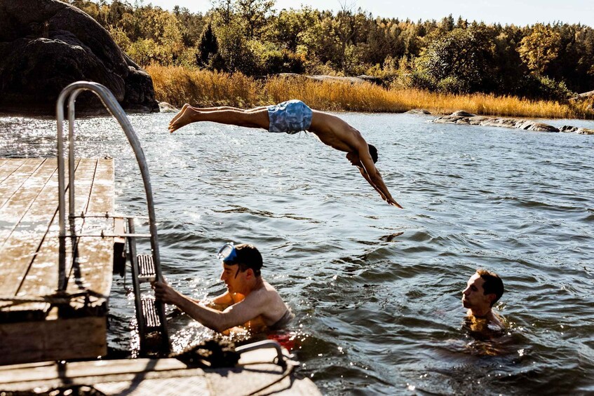 A person diving into a lake from a dock surrounded by trees. 3