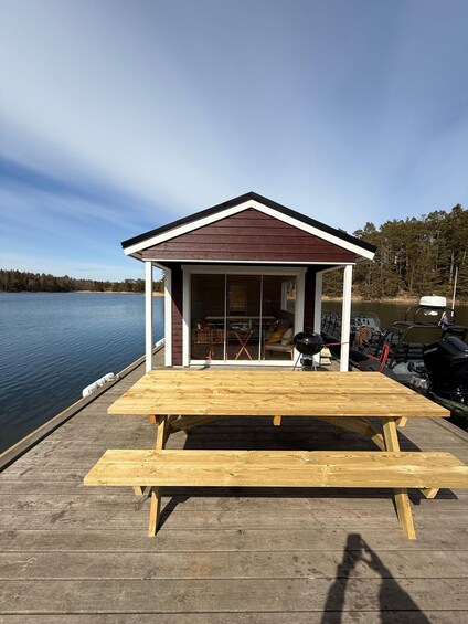A wooden dock with a picnic table and a covered area with a grill. 5