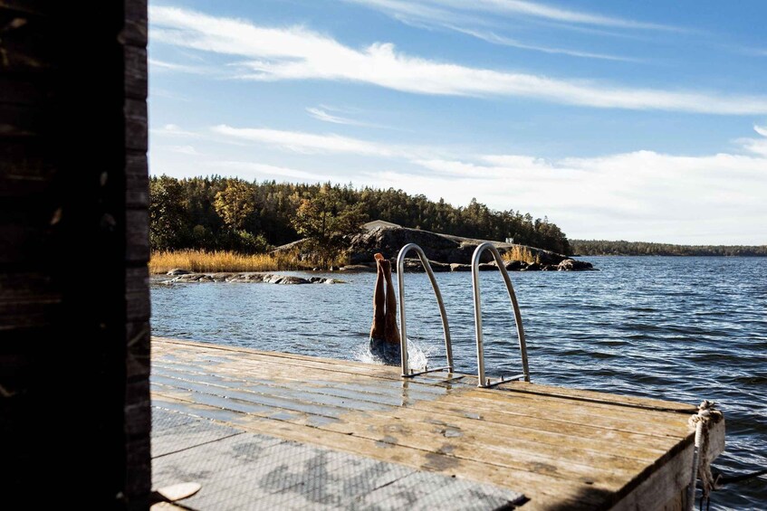A wooden dock extending into a lake with a person standing at the edge, surrounded by a forested shoreline. 4