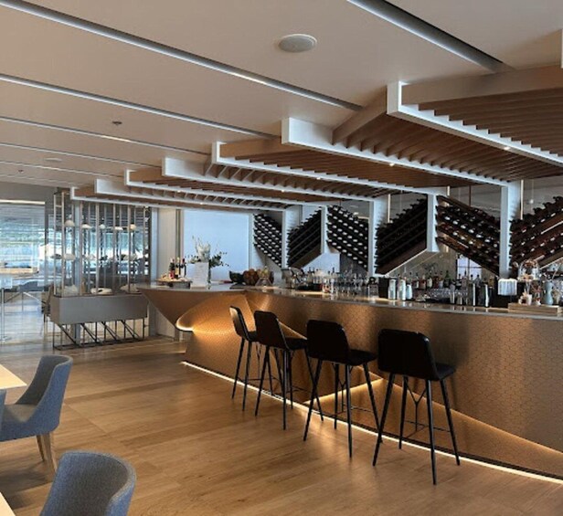 A modern bar with a wooden ceiling, a wine rack, and bar stools. 2