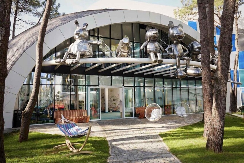 A modern building with a glass facade and a sculpture of bears on a curved structure above the entrance. 5
