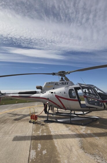 A helicopter with '4L-NAV' on its side parked on a tarmac. 4