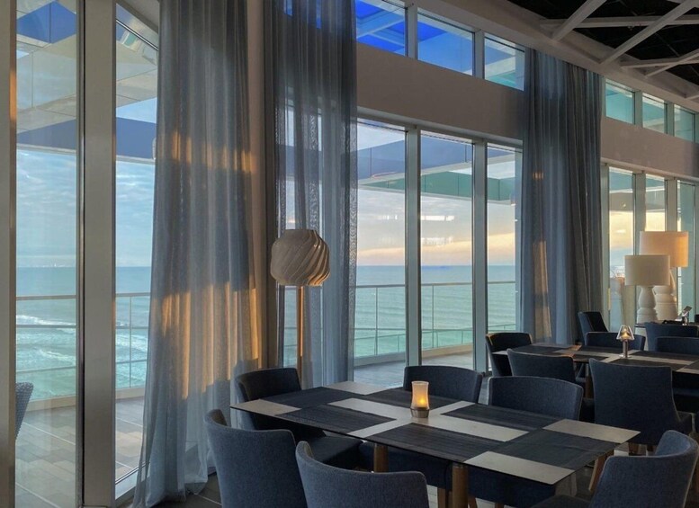 A modern dining area with large windows overlooking the ocean. 3