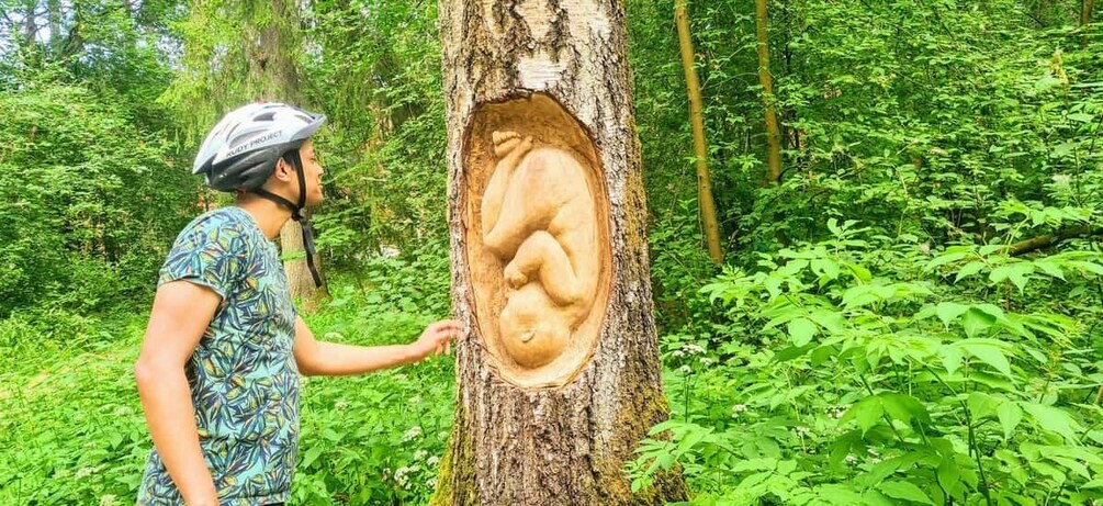 A person examining a tree with a carved human figure. 4