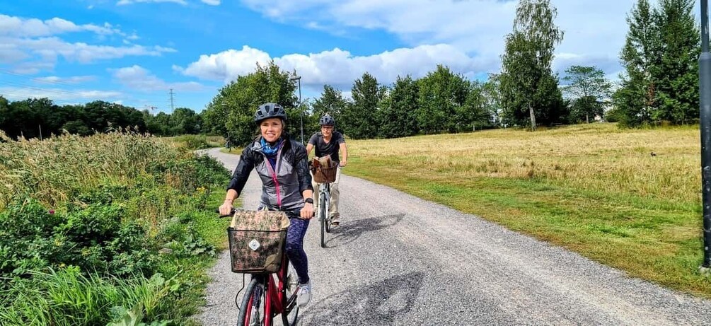 Two cyclists on a gravel path with greenery and trees in the background. 1