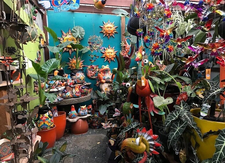 A vibrant market stall with colorful ceramic birds, sun motifs, and lush greenery. 3