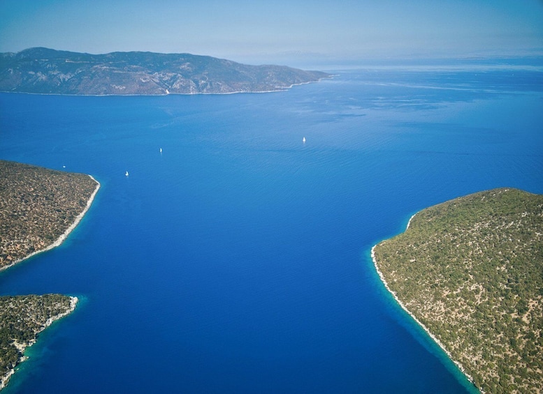 An aerial view of a coastal region with clear blue waters, two prominent peninsulas, and distant landforms. 4