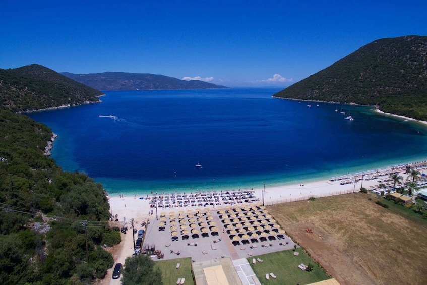 A coastal area with a large body of water, a beach, and a parking lot with numerous umbrellas. 5