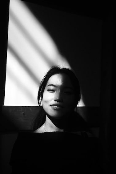 A person seated with sunlight casting shadows on a wall. 2