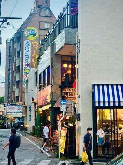 A street scene with pedestrians, a variety of storefronts, and a blue and white awning. 3