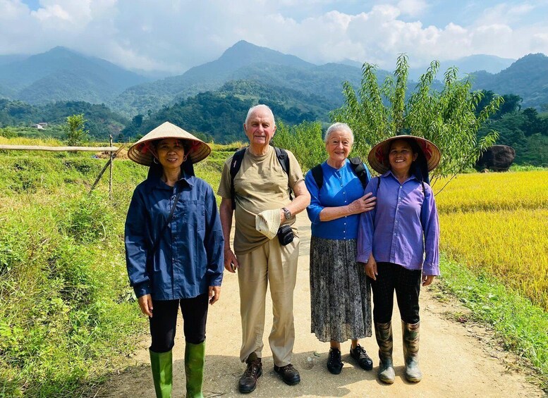 Four people standing on a dirt path with a mountainous landscape in the background. 3