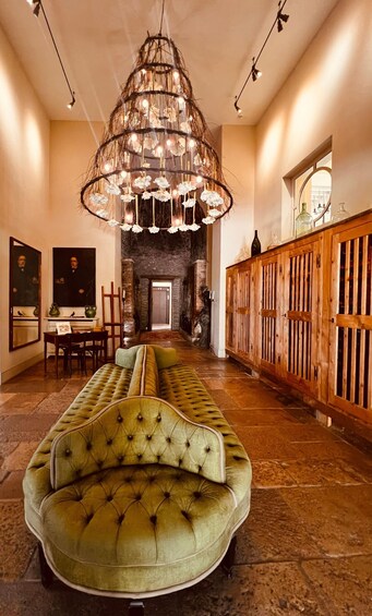 A luxurious interior with a green tufted sofa, a unique chandelier, and a wooden cabinet. 4