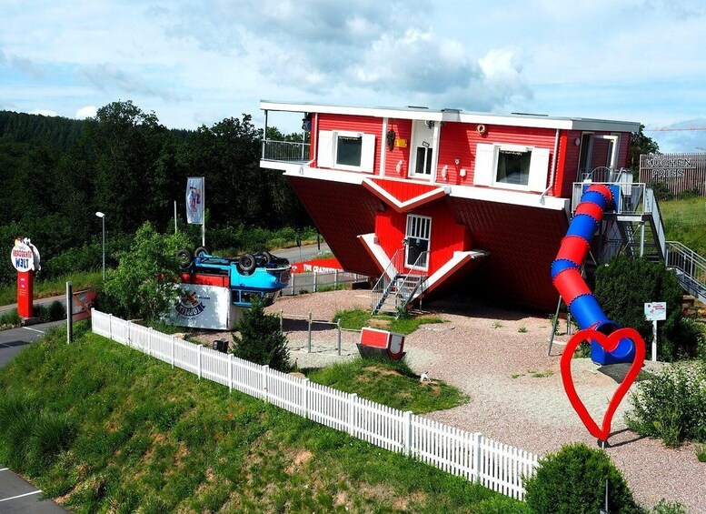 A red and white building with a blue slide, surrounded by greenery and a white fence. 4