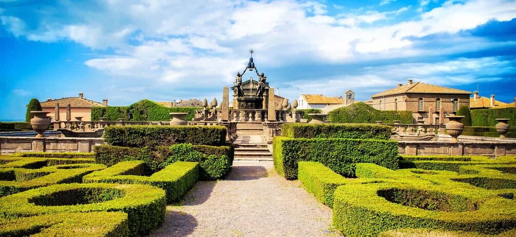 A formal garden with geometric hedges, a central fountain, and classical architecture. 5