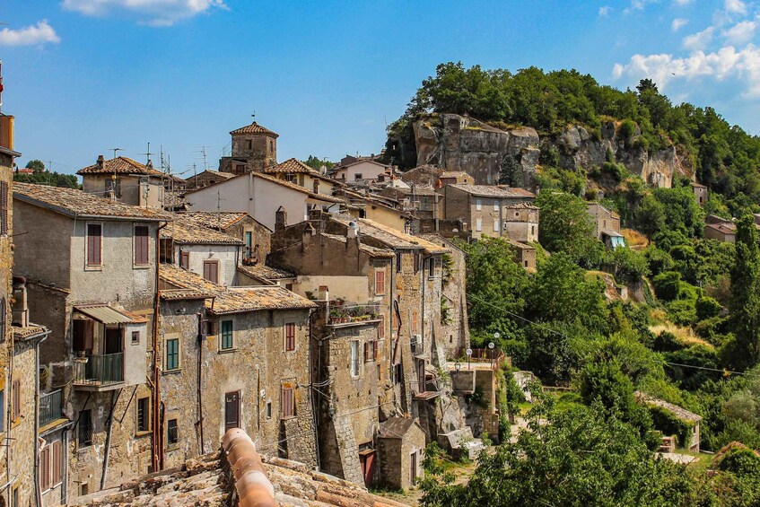 A historic village with terracotta-roofed buildings nestled in a hilly landscape. 2