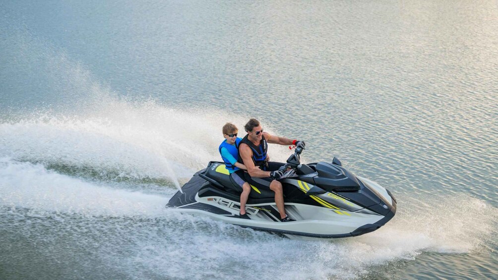 Two people on a jet ski moving across a body of water. 2