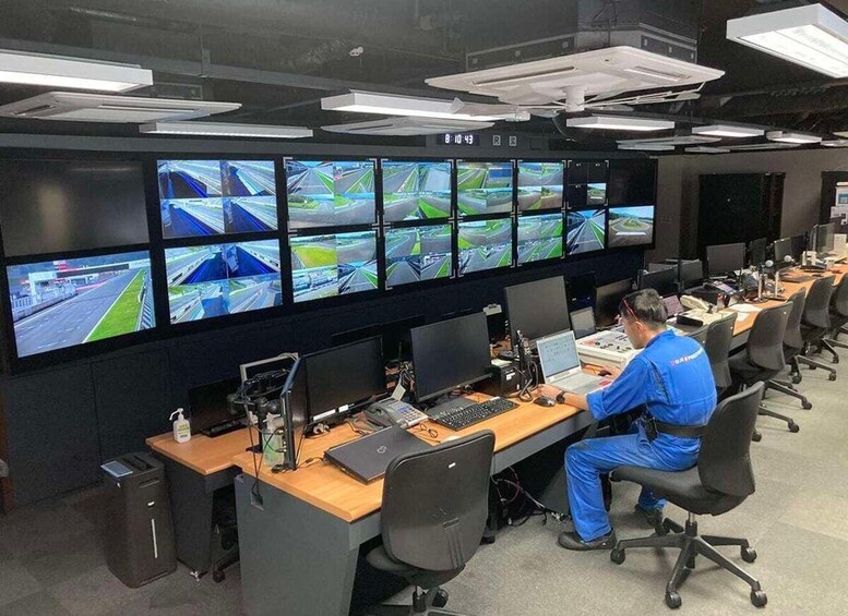 A control room with multiple monitors displaying traffic camera feeds, a person working at a desk, and office chairs. 5
