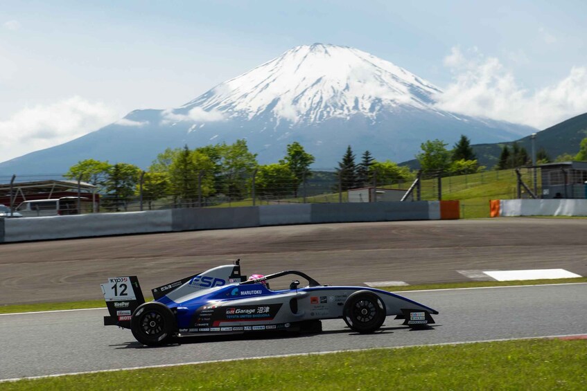 A race car on a track with a snow-capped mountain in the background. 1